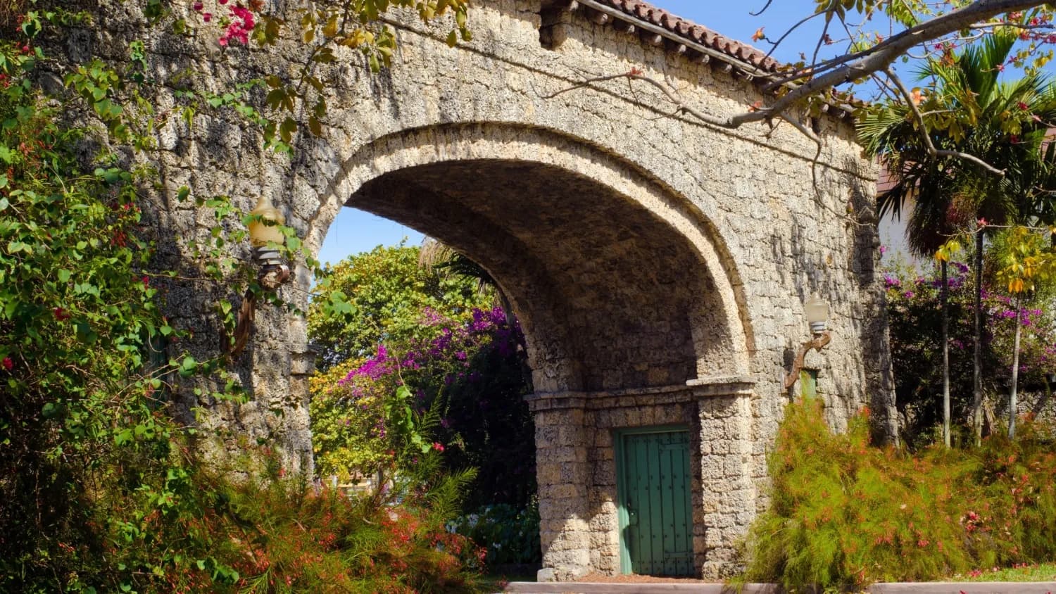 A coral-rock entrance arch in Coral Gables with bougainvillea